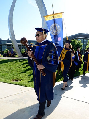Academic Senate Chair and Engineering Professor Jian-Qiao Sun carries the mace at Commencement 2015. 